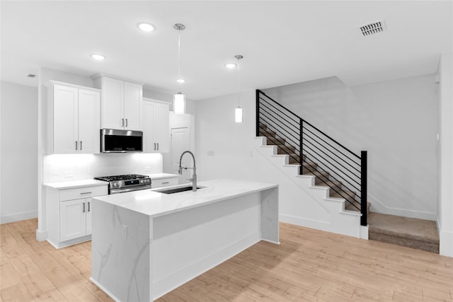 kitchen featuring sink, stainless steel appliances, hanging light fixtures, and white cabinets