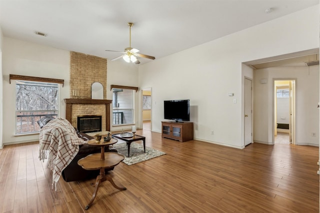 living area with baseboards, ceiling fan, wood finished floors, and a fireplace
