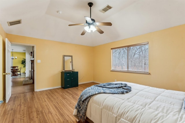 bedroom featuring vaulted ceiling, visible vents, baseboards, and light wood finished floors