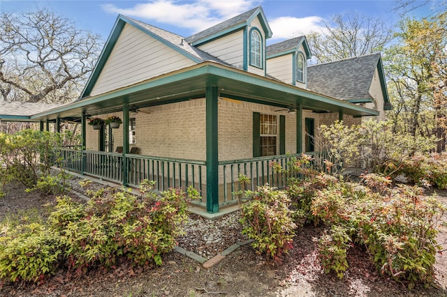view of home's exterior with brick siding, a ceiling fan, and covered porch