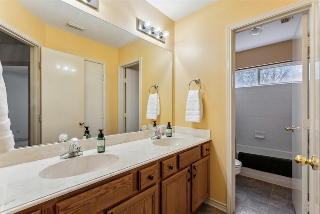 bathroom featuring double vanity, a sink, visible vents, and toilet