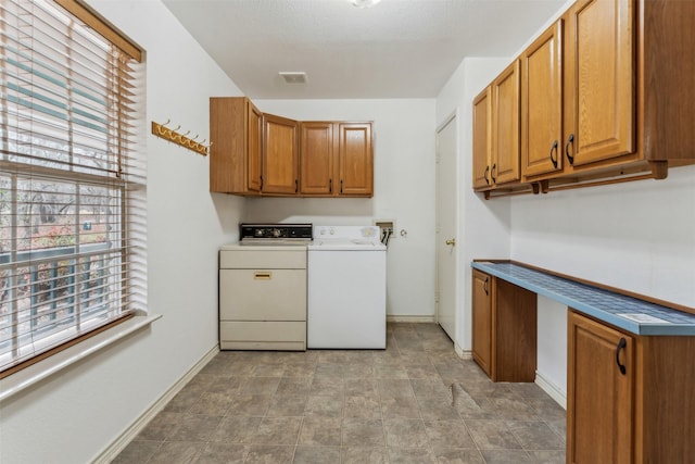 clothes washing area with washer and dryer, baseboards, cabinet space, and a wealth of natural light
