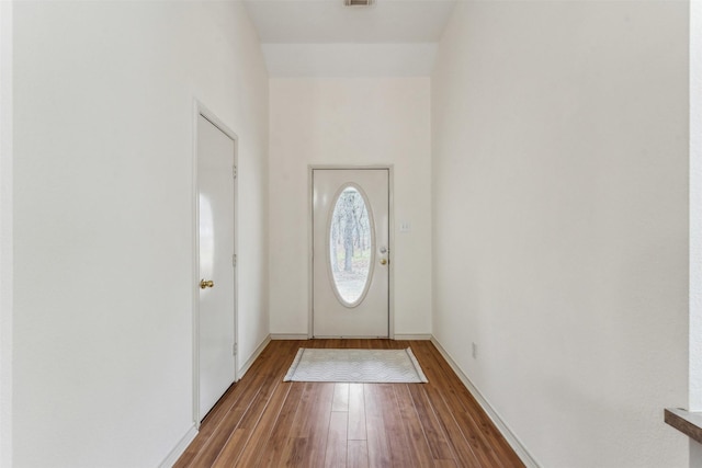 foyer entrance featuring baseboards, visible vents, and wood finished floors