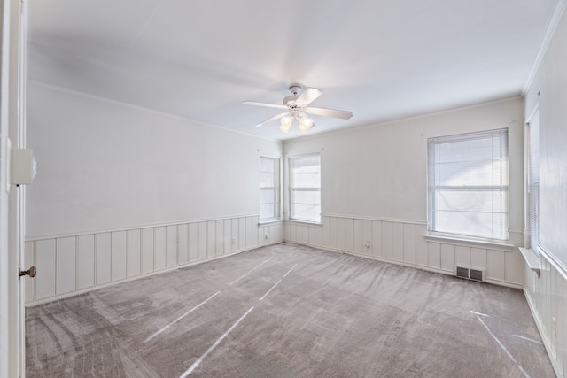 empty room featuring ceiling fan, light colored carpet, and ornamental molding