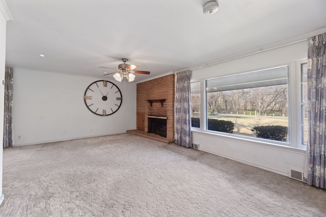 unfurnished living room featuring ceiling fan, a large fireplace, ornamental molding, and carpet floors