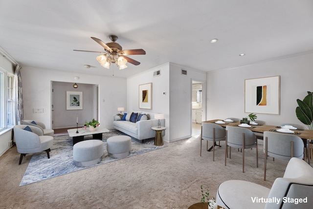 carpeted living room with ceiling fan and ornamental molding