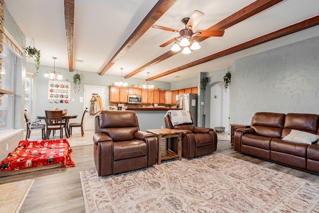 living room with ceiling fan with notable chandelier, light hardwood / wood-style flooring, and beamed ceiling