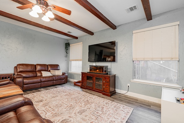 living room with hardwood / wood-style floors, ceiling fan, and beamed ceiling