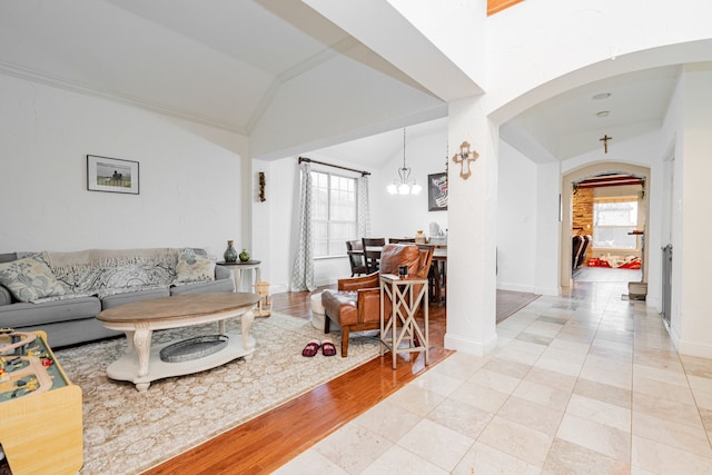 tiled living room featuring lofted ceiling, a notable chandelier, and a wealth of natural light