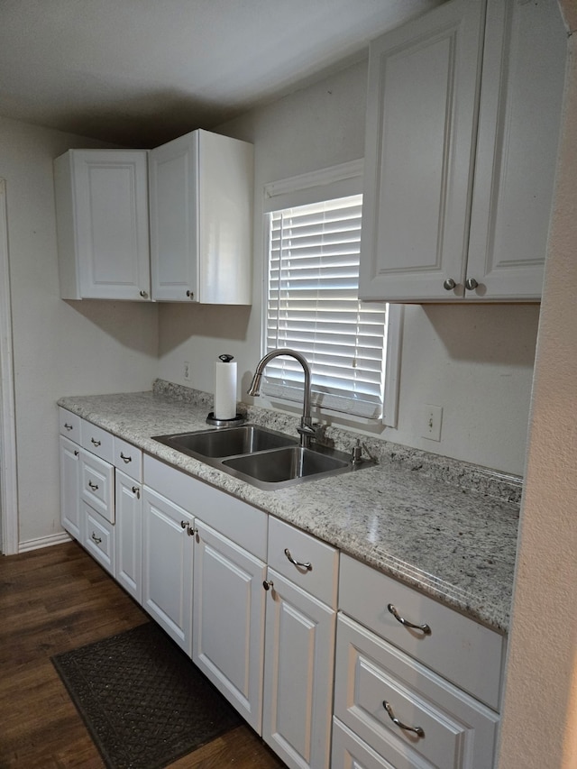 kitchen featuring white cabinetry, light stone countertops, sink, and dark hardwood / wood-style flooring