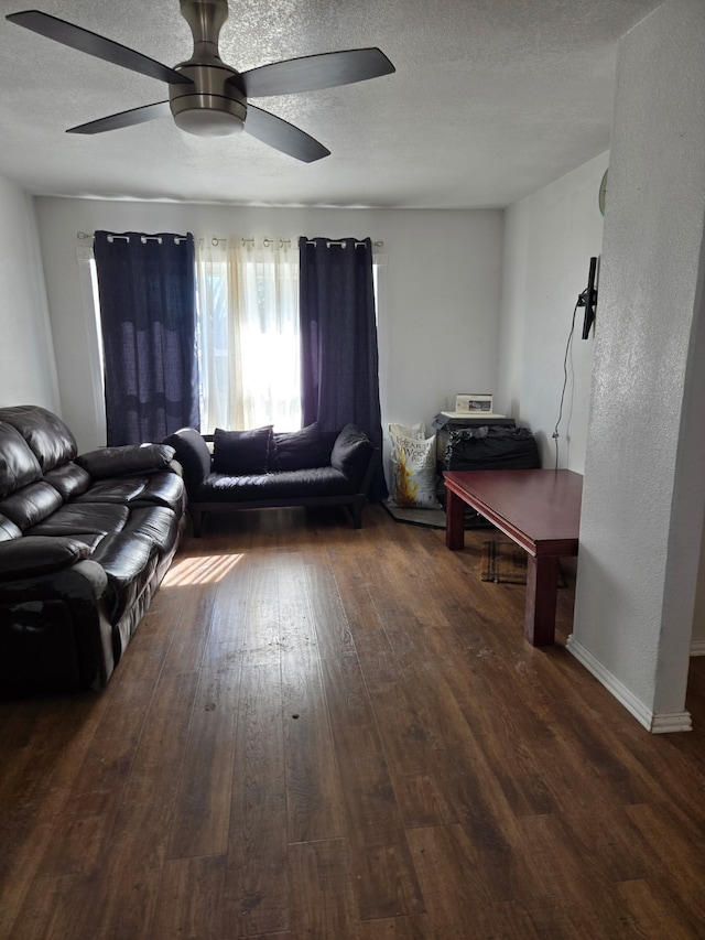 living room with ceiling fan, dark hardwood / wood-style floors, and a textured ceiling