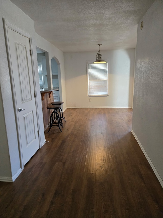 unfurnished dining area with dark wood-type flooring and a textured ceiling