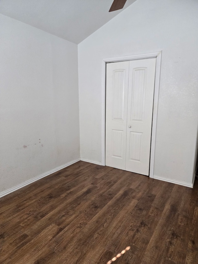 unfurnished bedroom featuring dark hardwood / wood-style flooring, vaulted ceiling, and a closet