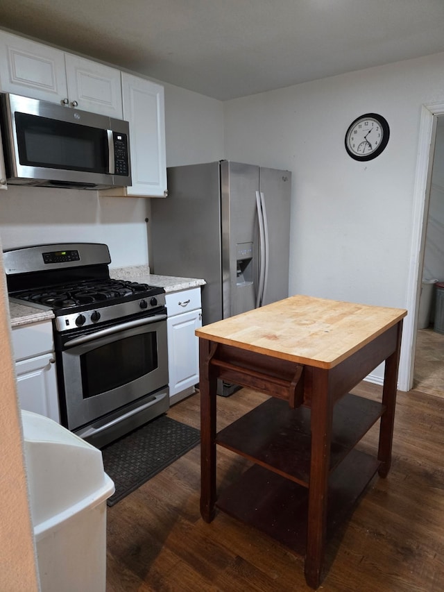 kitchen with dark hardwood / wood-style flooring, white cabinets, and appliances with stainless steel finishes