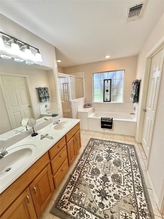 bathroom featuring a textured ceiling, separate shower and tub, vanity, and tile patterned floors