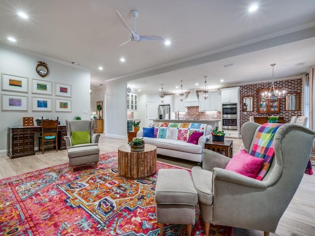 living room featuring ornamental molding, ceiling fan with notable chandelier, and light wood-type flooring