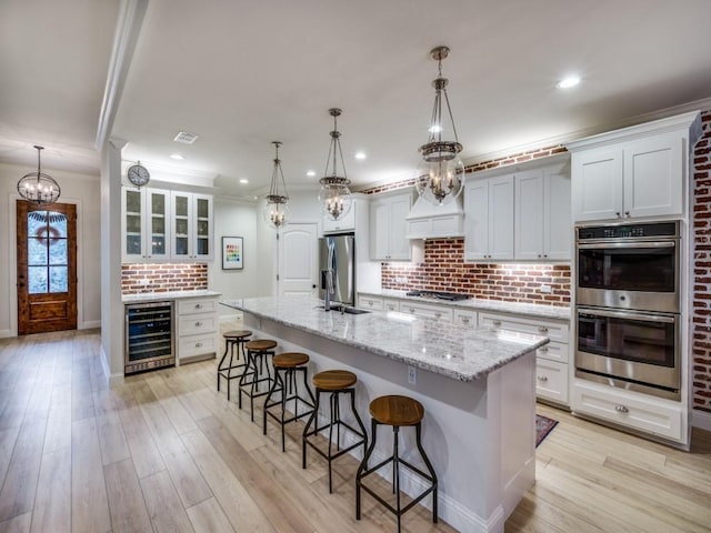 kitchen featuring white cabinetry, a large island, backsplash, and appliances with stainless steel finishes