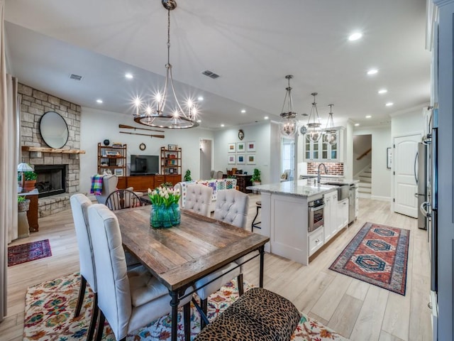 dining space featuring ornamental molding, a fireplace, and light hardwood / wood-style flooring