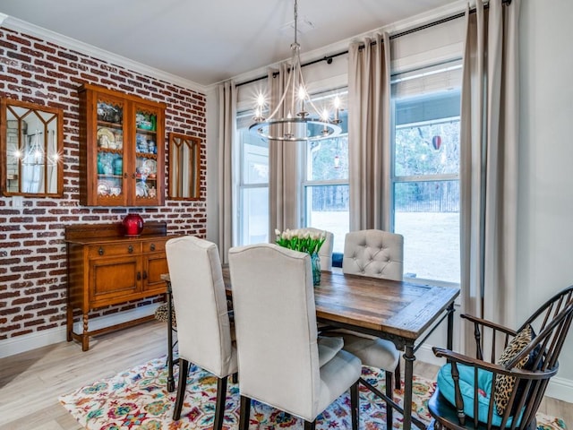 dining space with ornamental molding, brick wall, an inviting chandelier, and light hardwood / wood-style flooring