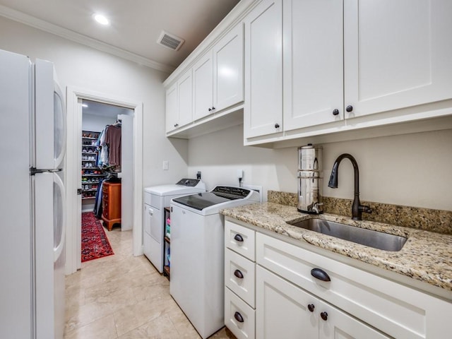 washroom featuring cabinets, ornamental molding, sink, and washing machine and dryer