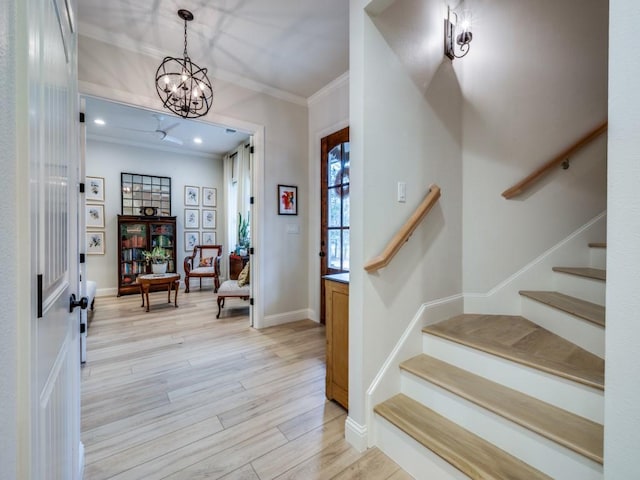 foyer entrance with crown molding, an inviting chandelier, and light hardwood / wood-style flooring