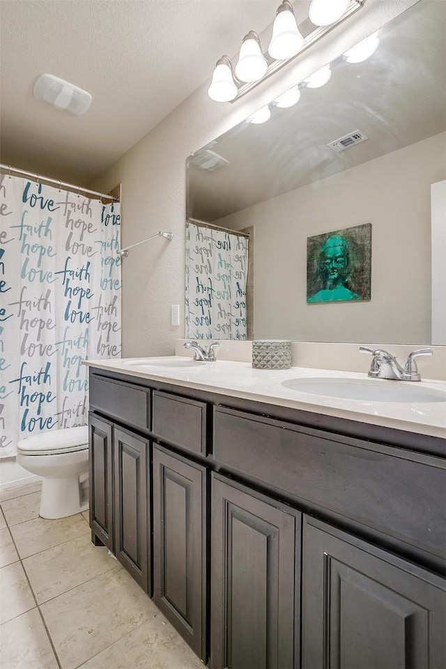 bathroom with tile patterned flooring, vanity, a textured ceiling, and toilet