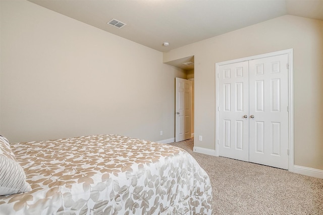 bedroom featuring vaulted ceiling, light carpet, and a closet