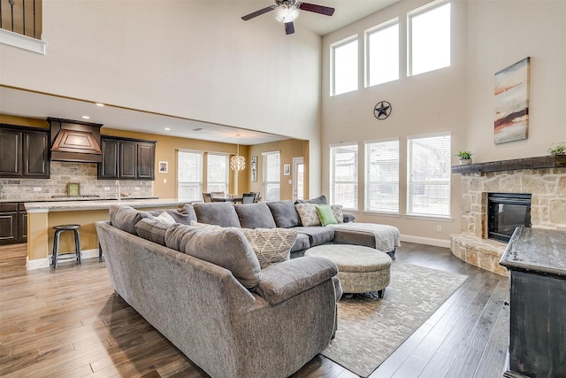 living room featuring ceiling fan, wood-type flooring, a fireplace, and plenty of natural light