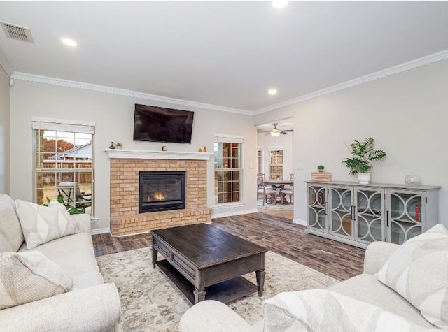 living room with hardwood / wood-style flooring, ornamental molding, and a brick fireplace