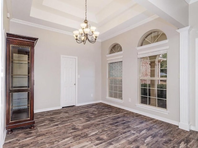 unfurnished dining area featuring decorative columns, dark hardwood / wood-style floors, an inviting chandelier, and a tray ceiling