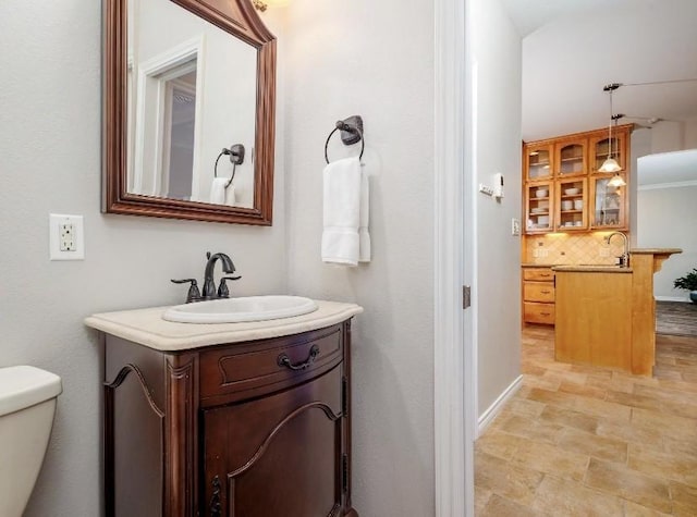 bathroom featuring vanity, toilet, and decorative backsplash