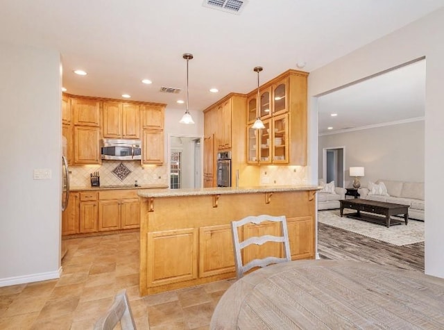 kitchen with tasteful backsplash, a kitchen breakfast bar, ornamental molding, kitchen peninsula, and stainless steel appliances