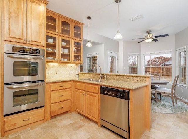 kitchen with appliances with stainless steel finishes, kitchen peninsula, sink, and decorative backsplash