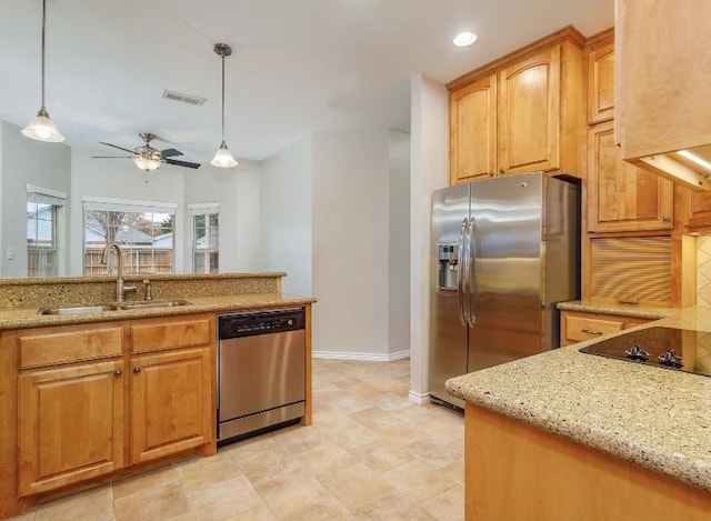 kitchen with pendant lighting, stainless steel appliances, light stone countertops, and sink