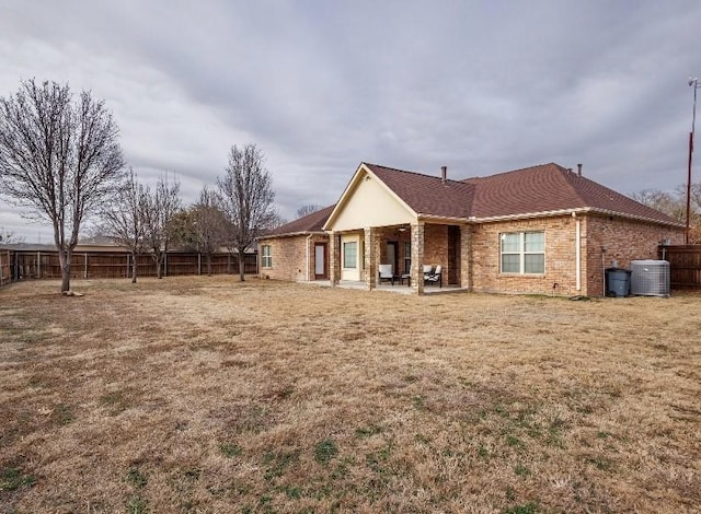 back of house with cooling unit, a patio area, and a lawn