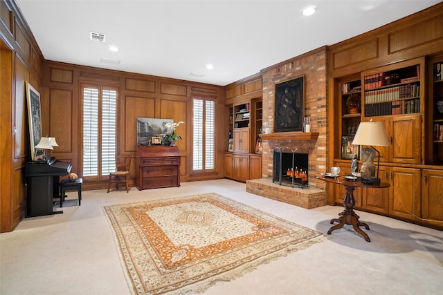 carpeted living room featuring crown molding, a brick fireplace, built in shelves, and wooden walls