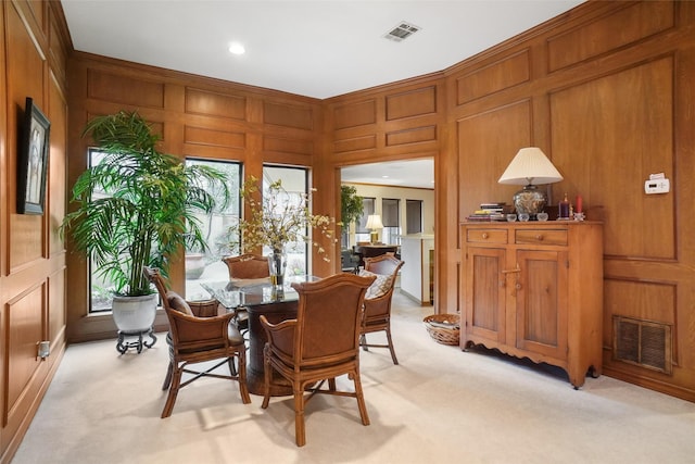 dining space featuring light carpet and wooden walls