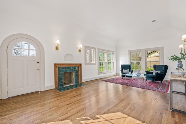 living room featuring a tiled fireplace and light wood-type flooring