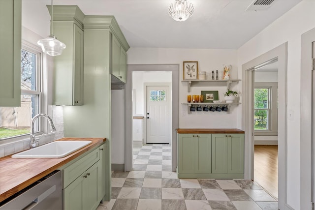 kitchen featuring pendant lighting, sink, dishwasher, green cabinets, and butcher block counters