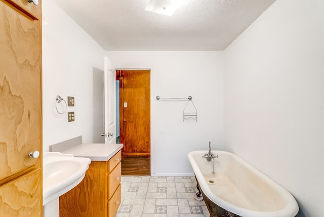 bathroom featuring a bath, sink, and a textured ceiling