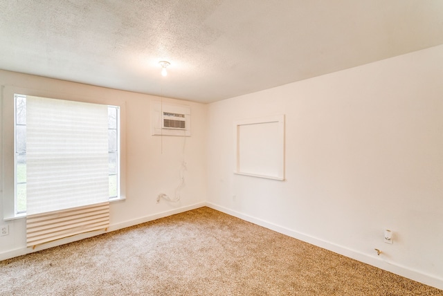 empty room featuring carpet floors, a wall unit AC, and a textured ceiling