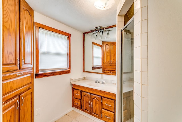 bathroom with a shower with door, vanity, tile patterned floors, and a textured ceiling