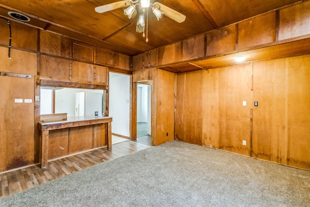 kitchen featuring wood ceiling, ceiling fan, wooden walls, white refrigerator with ice dispenser, and light colored carpet