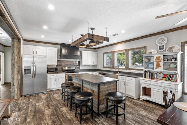 kitchen featuring a kitchen island, white cabinetry, sink, stainless steel appliances, and custom range hood