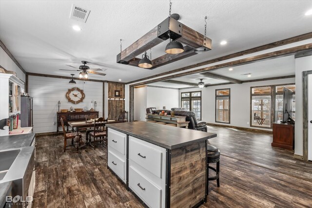 kitchen with ceiling fan, dark hardwood / wood-style flooring, a kitchen island, and white cabinets