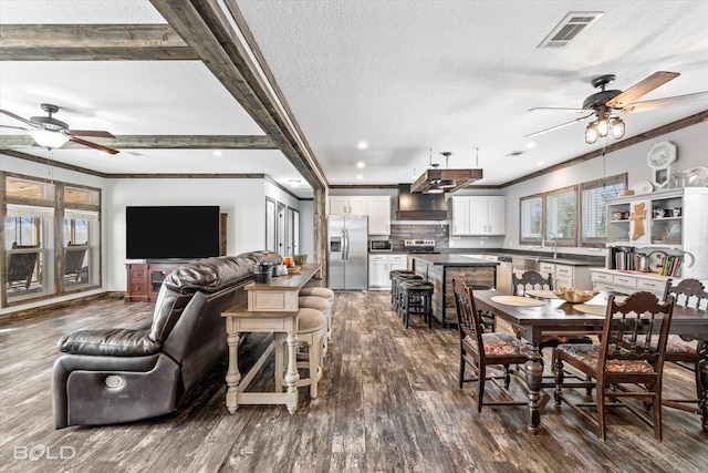 dining area featuring sink, hardwood / wood-style flooring, ornamental molding, ceiling fan, and a textured ceiling