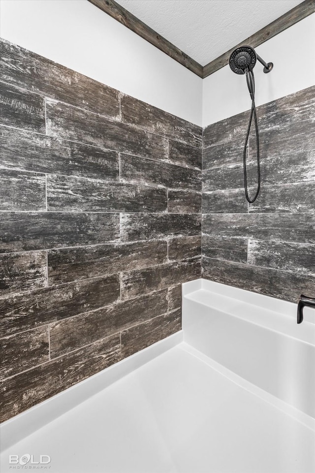 bathroom with a textured ceiling and a tile shower