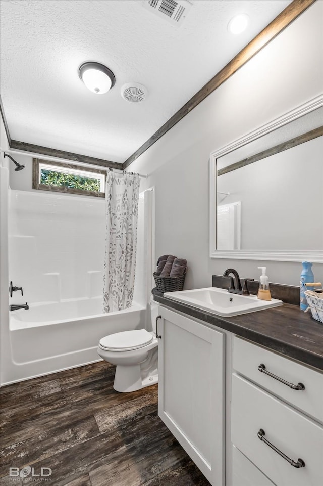 full bathroom with shower / tub combo with curtain, wood-type flooring, vanity, toilet, and a textured ceiling