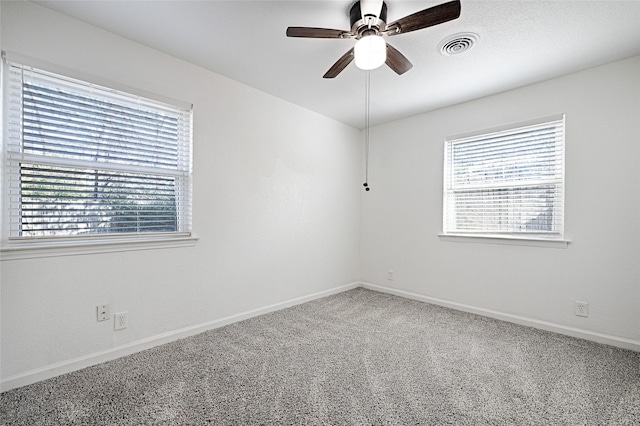 carpeted empty room with baseboards, visible vents, and ceiling fan