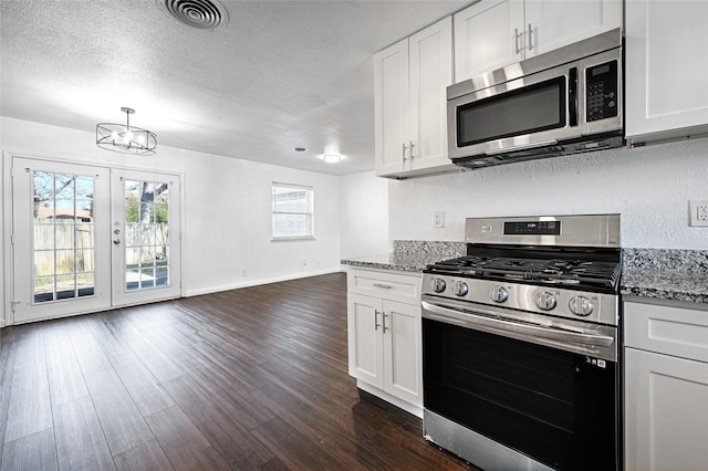 kitchen featuring visible vents, dark wood-style flooring, light stone countertops, stainless steel appliances, and a textured ceiling